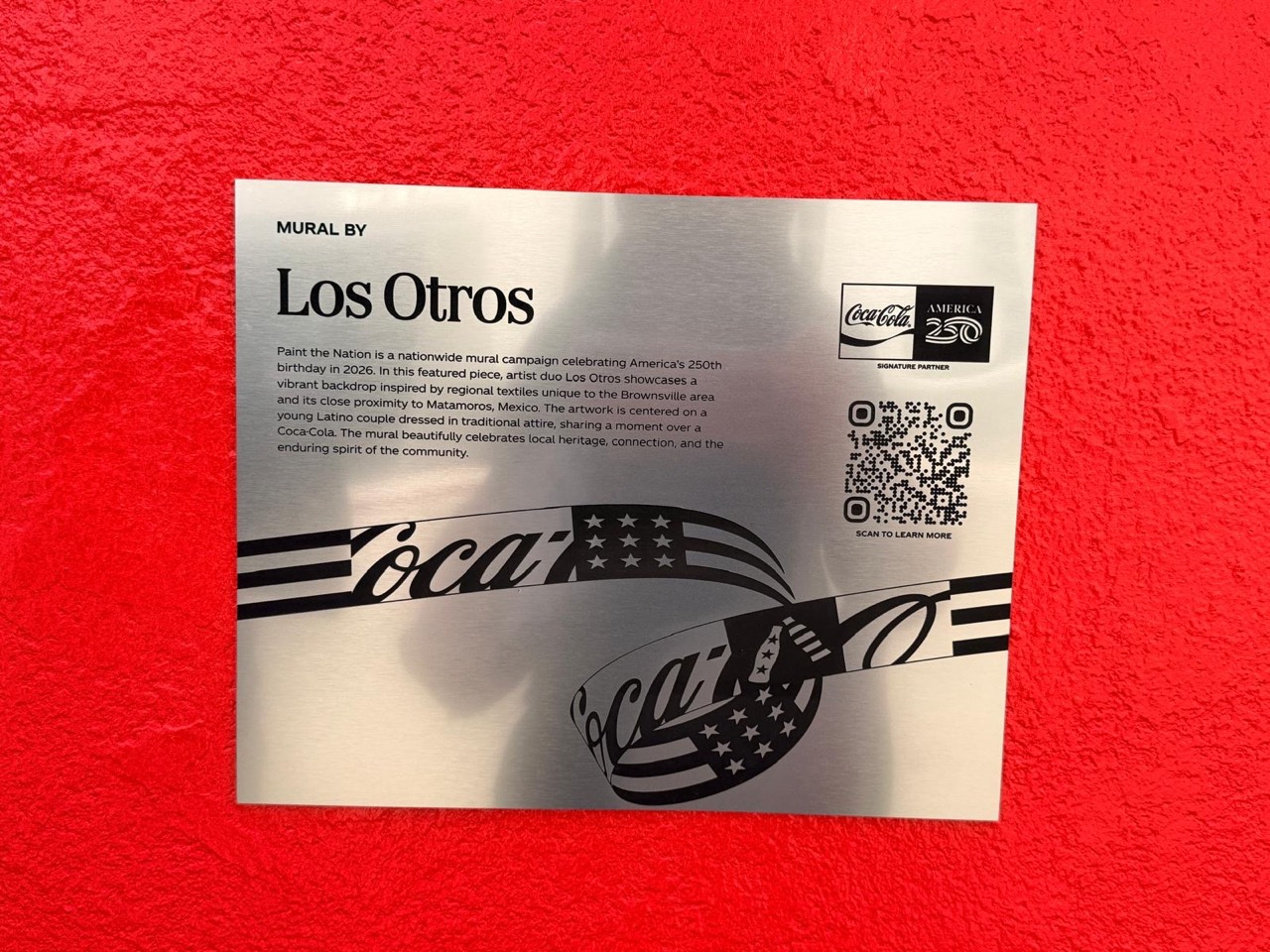 A plaque describes the Los Otros mural in Downtown Brownsville.