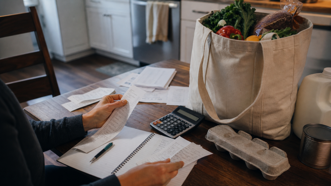Household reviewing a grocery receipt, utility bills and calculator at a kitchen table