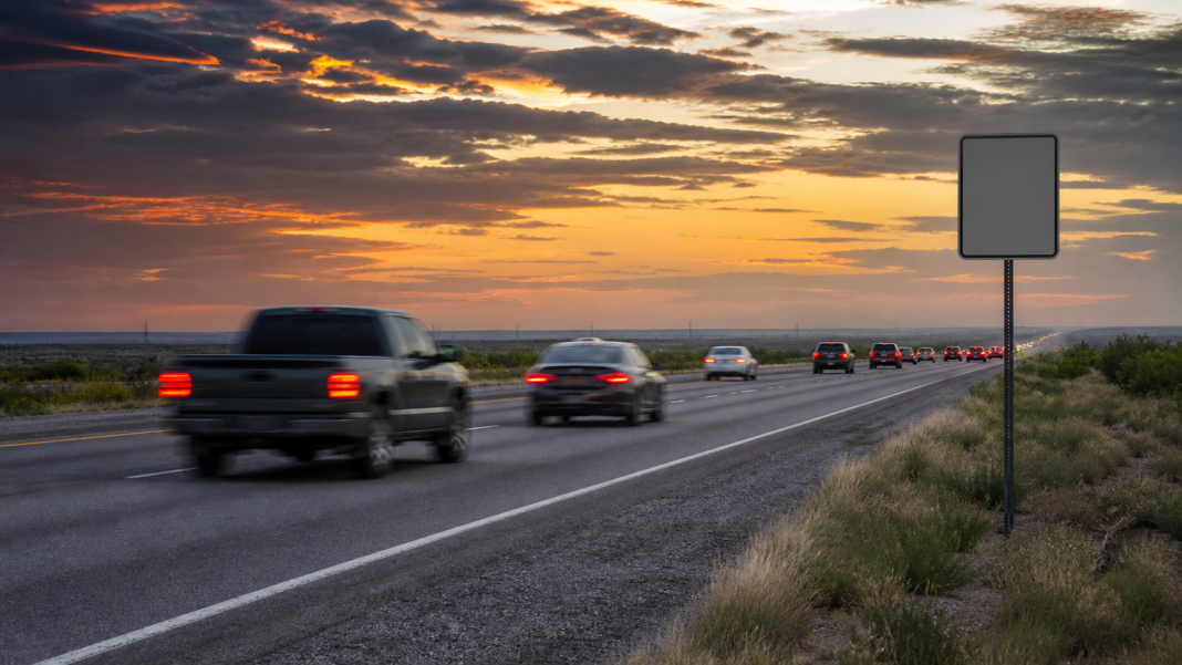 Traffic moving along a South Texas highway at dusk beside a speed-limit sign