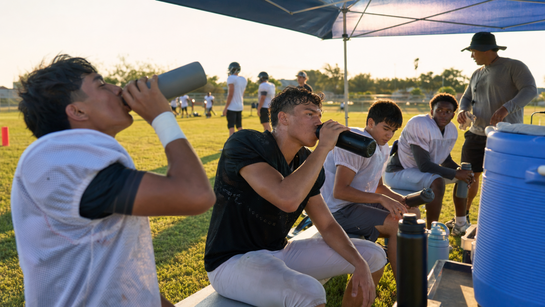 Student-athletes taking a supervised water break during outdoor practice